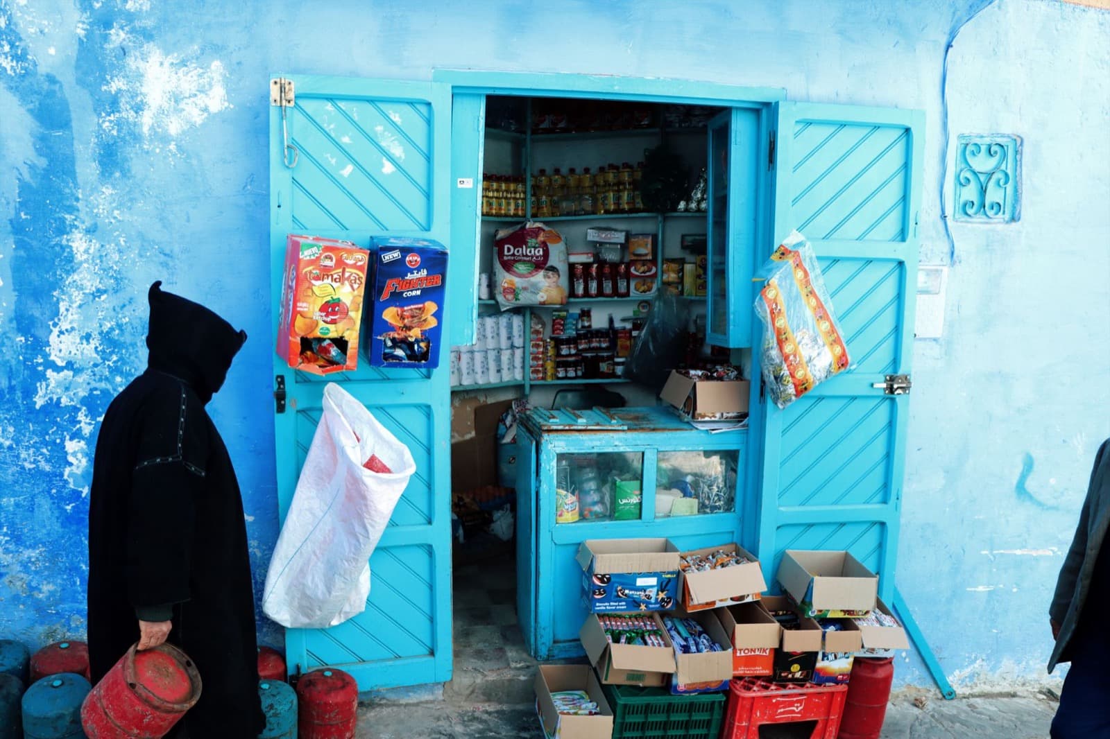 Épicerie aux murs bleus de Chefchaouen et un client en djellaba